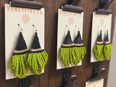 three pairs of earrings hanging from hooks on a wooden wall in front of a sign