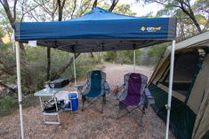 two camping chairs under a tent in the woods