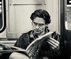 a man sitting on a subway reading a newspaper