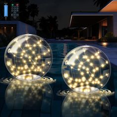 two lighted balls sitting on top of a swimming pool