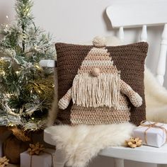 a crocheted pillow sitting on top of a white chair next to a christmas tree