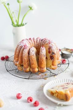 a bundt cake with powdered sugar and cranberries on a wire rack