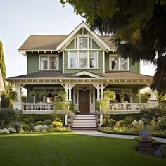 a large green house with lots of trees and bushes on the front lawn in front of it