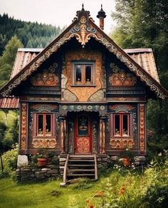 a small wooden house in the middle of some grass and trees with mountains in the background