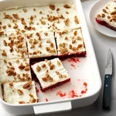 there are many pieces of cake in the pan with white frosting and pecans on top