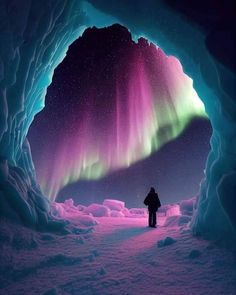 a person standing in front of an ice cave with the aurora bore visible above it