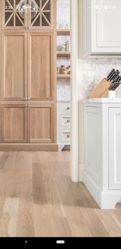 a kitchen with white cabinets and wood flooring in the center is an open pantry