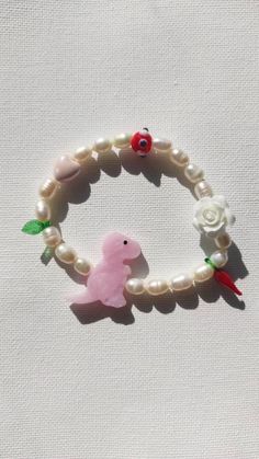 a bracelet with a pink toy bird and flowers on it