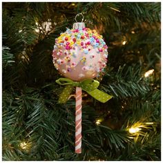 an ornament hanging from a christmas tree decorated with sprinkles and candy