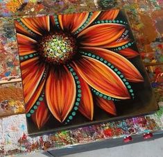 an orange flower painted on top of a piece of art