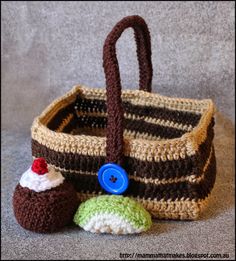 a crocheted basket with two small cupcakes and a button on it