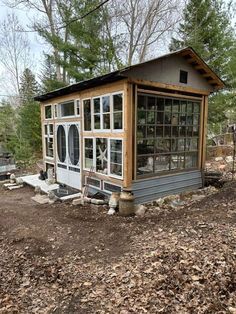 a small house sitting in the middle of a forest with lots of leaves on the ground