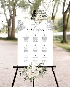 a seating sign with white flowers and greenery on it