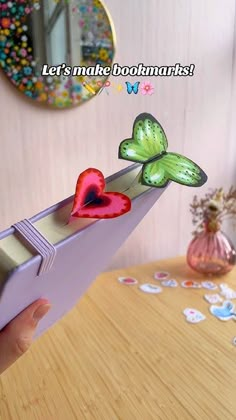 a person is holding an origami box with hearts and butterflies on it,