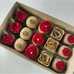 twelve cupcakes in a box decorated with red and gold flowers on each one