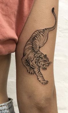 a woman's arm with a tiger tattoo on the left side of her leg