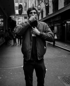 a man is standing on the street eating something