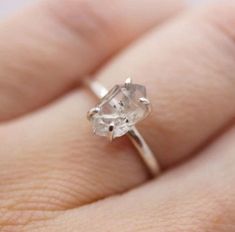 a woman's hand holding an engagement ring with a white diamond in the middle