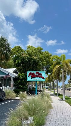 a street sign on the side of a road next to palm trees