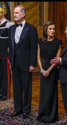 two men and one woman are standing in front of an official man wearing a uniform