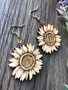 These beautiful laser cut & etched sunflower earrings are made from 1/8" Maple hardwood. They’re light as a feather and ideal for daily wear! Choose either gold tone or silver tone hardware. Ear wires are stainless steel. Wood part of earring measures approximately 1.6” round at the widest parts. Laser cut, crafted by hand and shipped from the United States. Wood grain varies with every piece and computer monitor settings can vary which may result in displaying slight color differences. You shou Laser Cut Wood Earrings, Engraved Earrings, Engraving Ideas, Laser Art, Sunflower Earrings, Light As A Feather, Steel Wood, Maple Hardwood, Nature Inspired Jewelry