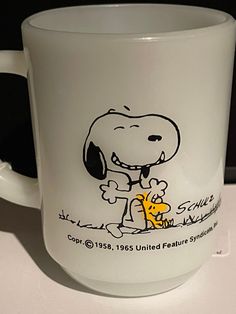 a glass coffee mug with a drawing of a snoopy dog holding a yellow object