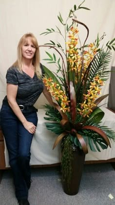 a woman standing next to a vase with yellow flowers