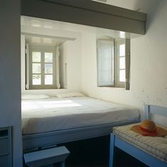 a bed room with a neatly made bed next to a window and a small table