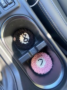 two crocheted balls in the center console of a car with numbers on them