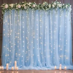 a blue backdrop with white flowers and candles