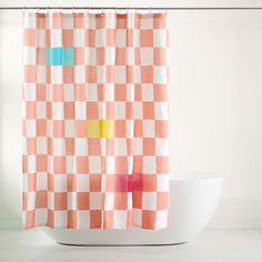 a white toilet sitting next to a checkered shower curtain with colorful squares on it