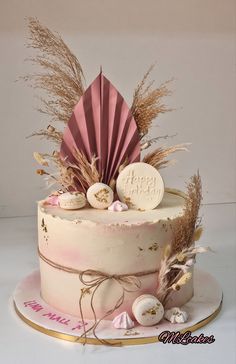 a birthday cake decorated with feathers, seashells and an umbrella on a plate