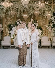 a man and woman standing next to each other in front of a chandelier