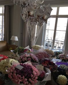 a bunch of flowers sitting on top of a table in front of two large windows