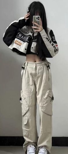 a woman taking a selfie in front of a mirror wearing cargo pants and white sneakers