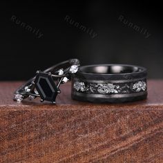 two wedding bands with black diamonds and white sapphires on top of a wooden table