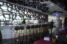 a bar with marble counter tops and stools in front of an artistic wall design