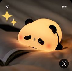 a lamp that looks like a panda bear laying down on a bed with its eyes closed