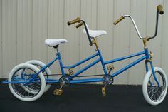 a blue and white bicycle parked in front of a metal building with no wheels on it