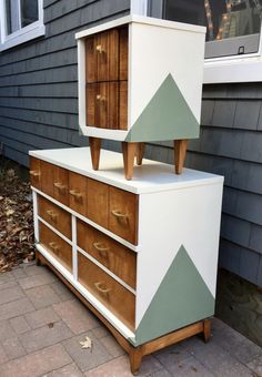 an old dresser is painted white and has green arrows on the top, along with two matching drawers