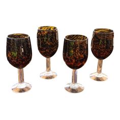 four wine glasses sitting next to each other on top of a white surface with an animal print pattern