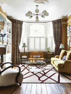 a living room filled with lots of furniture next to a window covered in curtains and drapes