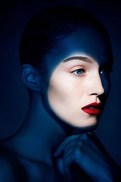 a woman with blue hair and red lipstick posing for a photo in the dark night