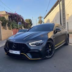 a black mercedes cla parked on the street in front of a building with yellow trim