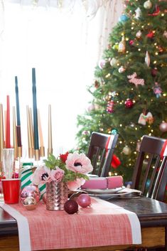 a dining room table set for christmas with candles and ornaments on the table next to it