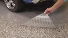 a man is sanding down the floor next to his car