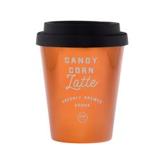 an orange cup with black lid sitting on top of a white table next to the words candy corn latte