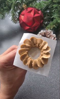 a person holding up a piece of food in front of a christmas ornament