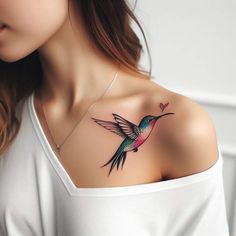 a woman's chest with a hummingbird tattoo on her left shoulder and heart in the middle