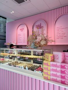 a bakery with pink walls and shelves filled with donuts, pastries and cakes